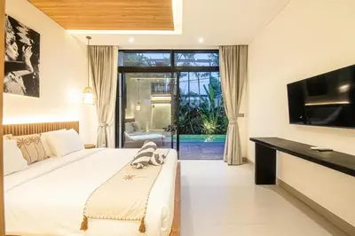 a bedroom with a large bed and a television at Elegant 5BR Modern Villa Steps from Café Del Mar in Canggu