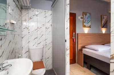 a bathroom with a sink and a toilet and a bed at Hotel Dakozi Living in Kuta