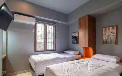 a bedroom with two beds and a window at Hotel Dakozi Living in Kuta