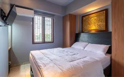 a bedroom with a large bed with a painting on the wall at Hotel Dakozi Living in Kuta
