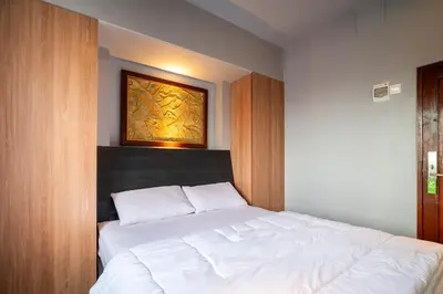 a bedroom with a white bed and a painting on the wall at Hotel Dakozi Living in Kuta