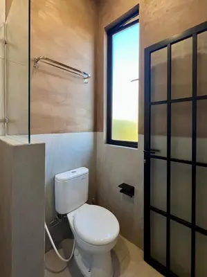 a bathroom with a toilet and a window at De Kamar Mezzanine in Denpasar