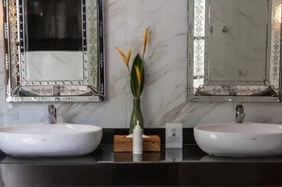 a bathroom with two sinks and two mirrors at Villa Balidamai in Kerobokan