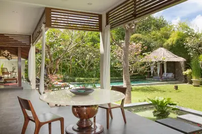a patio with a table and chairs and a pool at Villa Balidamai in Kerobokan