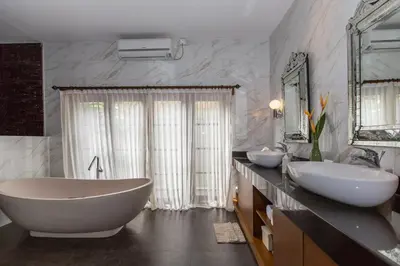 a bathroom with two sinks and a tub and mirrors at Villa Balidamai in Kerobokan