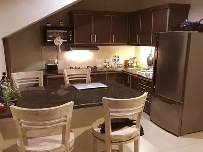 a kitchen with a counter with chairs and a refrigerator at Villa Anyelir in Seminyak