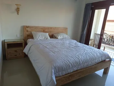 a bedroom with a bed with a wooden headboard and a window at Erick house in Seminyak