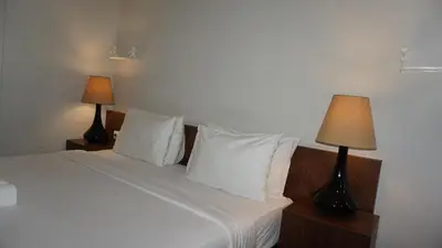 a bedroom with a white bed with two lamps at Ambengan Tenten By BMI in Denpasar