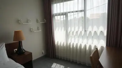 a bedroom with a window with curtains and a bed at Ambengan Tenten By BMI in Denpasar