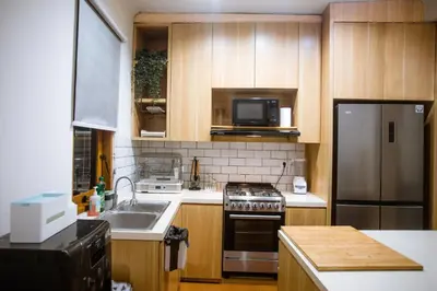 a kitchen with wooden cabinets and a stainless steel refrigerator at Jemma Home Warm & Simple 3BR Stay in Denpasar near Sanur in Pesanggaran