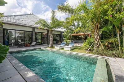 a swimming pool in front of a house with palm trees at Luxury 3BR Modern Villa in the Heart of Seminyak in Seminyak