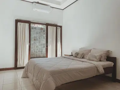 a bedroom with a large bed and a window at Kubu Van Helen in Legian
