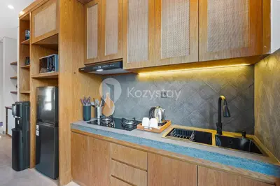 a kitchen with wooden cabinets and a black refrigerator at Gracia Villa by Kozystay - Jimbaran in Jimbaran