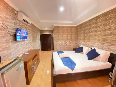 a bedroom with a bed and a tv on a brick wall at ABI Hotel2 - 1 minute to the Beach and 1 second to the Mall in Ngurah Rai International Airport