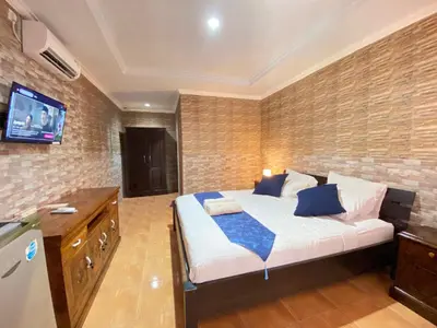 a bedroom with a bed and a tv on a brick wall at ABI Hotel2 - 1 minute to the Beach and 1 second to the Mall in Ngurah Rai International Airport