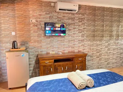 a bedroom with a tv on a brick wall at ABI Hotel2 - 1 minute to the Beach and 1 second to the Mall in Ngurah Rai International Airport
