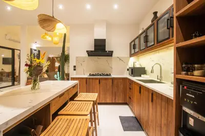 a kitchen with wooden cabinets and a counter with stools at Villa ADDI 4bedrooms Oberoi in Seminyak