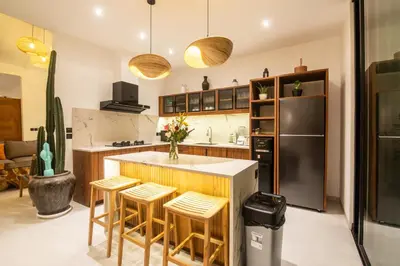 a kitchen with a counter with stools and a refrigerator at Villa ADDI 4bedrooms Oberoi in Seminyak