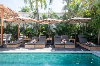 a pool with chairs and umbrellas next to a pool at Villa ADDI 4bedrooms Oberoi in Seminyak
