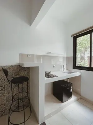 a kitchen with a counter and a stool in it at Sukanadi's Homestay in Legian