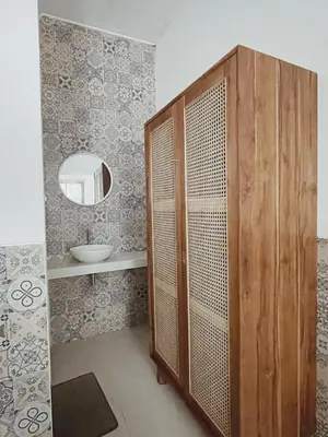 a bathroom with a wooden shower stall and a mirror at Sukanadi's Homestay in Legian