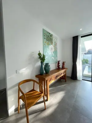 a living room with a wooden table and a chair at Sunflower Bali Villa 3BR Legian Double Six Beach in Seminyak