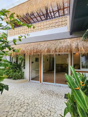 an outside view of a building with a straw roof at Villa Vela in the heart of Seminyak in Seminyak