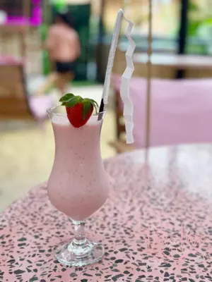 a drink with a strawberry in a glass on a table at Villa Vela in the heart of Seminyak in Seminyak