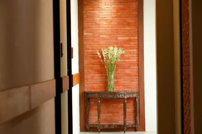 a vase of flowers on a table next to a brick wall at The Visala Boutique Suites Seminyak in Seminyak
