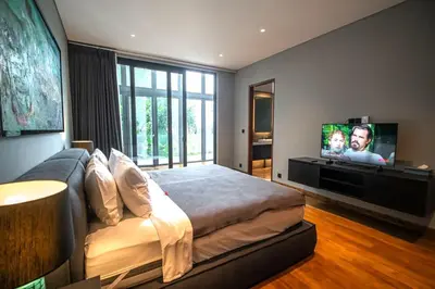 a bedroom with a large bed and a flat screen tv at Lillypad 5Bed Villa in Seminyak