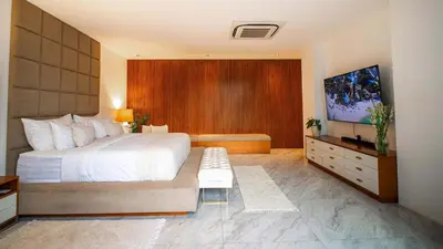 a bedroom with a large white bed and a flat screen tv at House of Light 5bed villa in Canggu