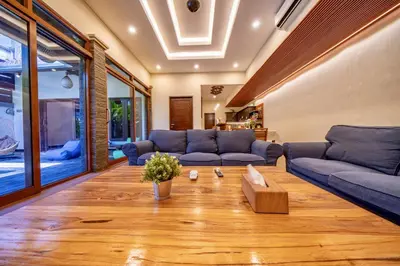 a living room with blue couches and a wooden floor at Seminyak Happy Villa in Legian