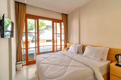 a bedroom with a large bed and a large window at AA Inn Kuta Beach in Ngurah Rai International Airport