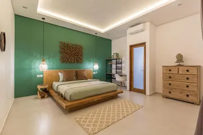 a bedroom with a bed and a green wall at VILLA BIBA cosy and stylish in Canggu