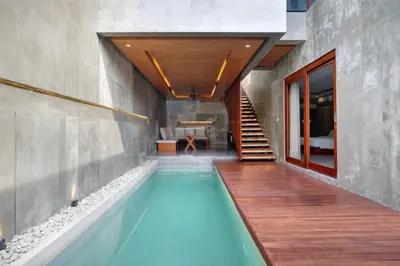 a swimming pool in a house with a wooden deck at Aqilah Villa Bali in Legian