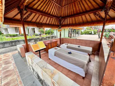 a covered patio with two beds and a table at Apartment at Jayakarta Residence Beach Front Access in Seminyak