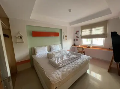 a bedroom with a bed with a green and red headboard at Apartment Keluarga di Kuta Bali in Kuta