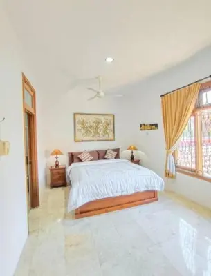 a white bedroom with a large bed and windows at Villa Mimi Mesari Kuta Bali in Kuta