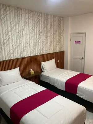 a hotel room with two beds with red and white sheets at Hotel Sanrina Kuta Bali in Kuta