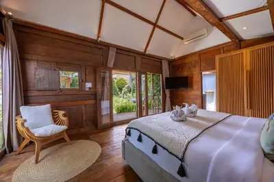 a bedroom with a large bed and a chair at Villa Sebelah by Optimum Bali Villas in Seminyak