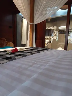 a bedroom with a bed with a black and white comforter at Navalia Rumah Kayu in Kerobokan