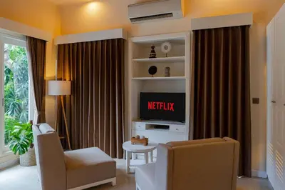 a living room with a tv and a chair at Boholuma Villas by Pertama Management in Seminyak