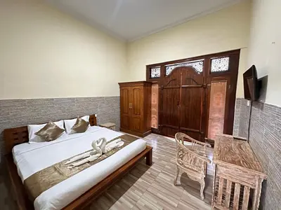 a bedroom with a bed and a chair in it at Osa Guest House 5 in Seminyak