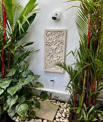 a stone plaque on the side of a wall with plants at Villa Kazari Zen in Seminyak