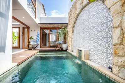 a pool in a house with a stone wall at Villa Monstera A7 By Aishwarya International in Kerobokan