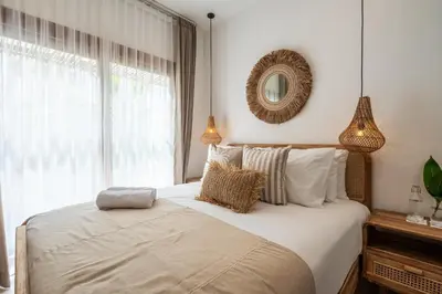 a bedroom with a bed with a mirror and a window at Villa Monstera A7 By Aishwarya International in Kerobokan