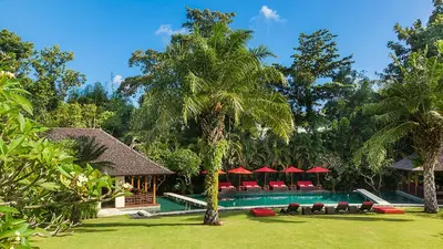 a resort with a swimming pool with chairs and trees at Villa The Beji in Canggu