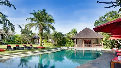 a resort swimming pool with chairs and a gazebo at Villa The Beji in Canggu