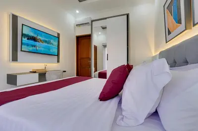 a bedroom with a large white bed with red pillows at Stylish 3BR Villa Sandalwood near Beach in Seminyak