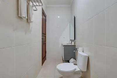 a white bathroom with a toilet and a sink at Stylish 3BR Villa Sandalwood near Beach in Seminyak